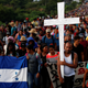 Migrants carry a Honduran flag and a cross in Pijijiapan, Mexico.